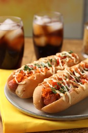 Delicious hot dogs with bacon, carrot and parsley on table, closeup