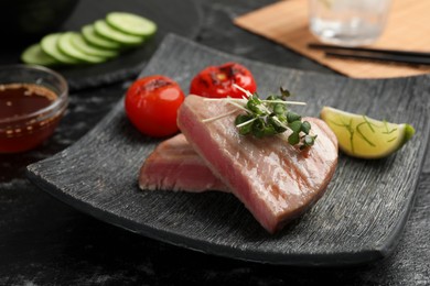 Photo of Pieces of delicious tuna with microgreens, lime and tomatoes on table, closeup