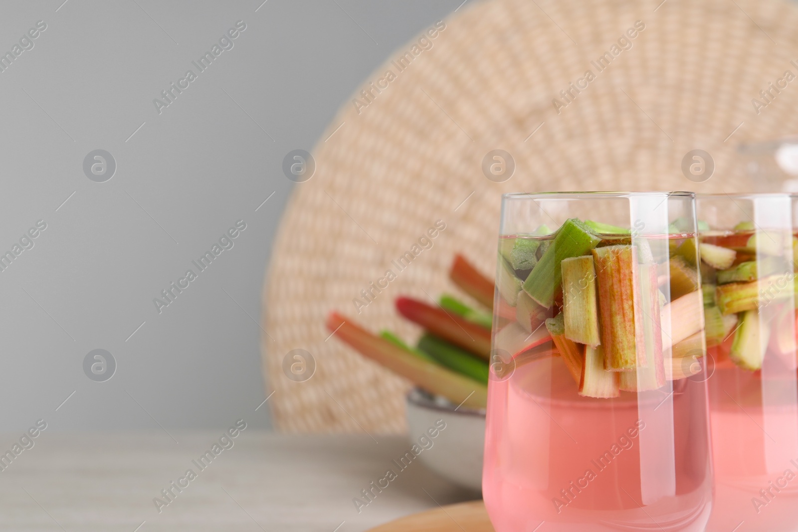 Photo of Glasses of tasty rhubarb cocktail on white wooden table, space for text
