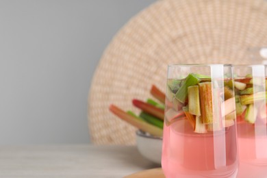 Glasses of tasty rhubarb cocktail on white wooden table, space for text