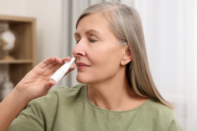 Medical drops. Woman using nasal spray indoors