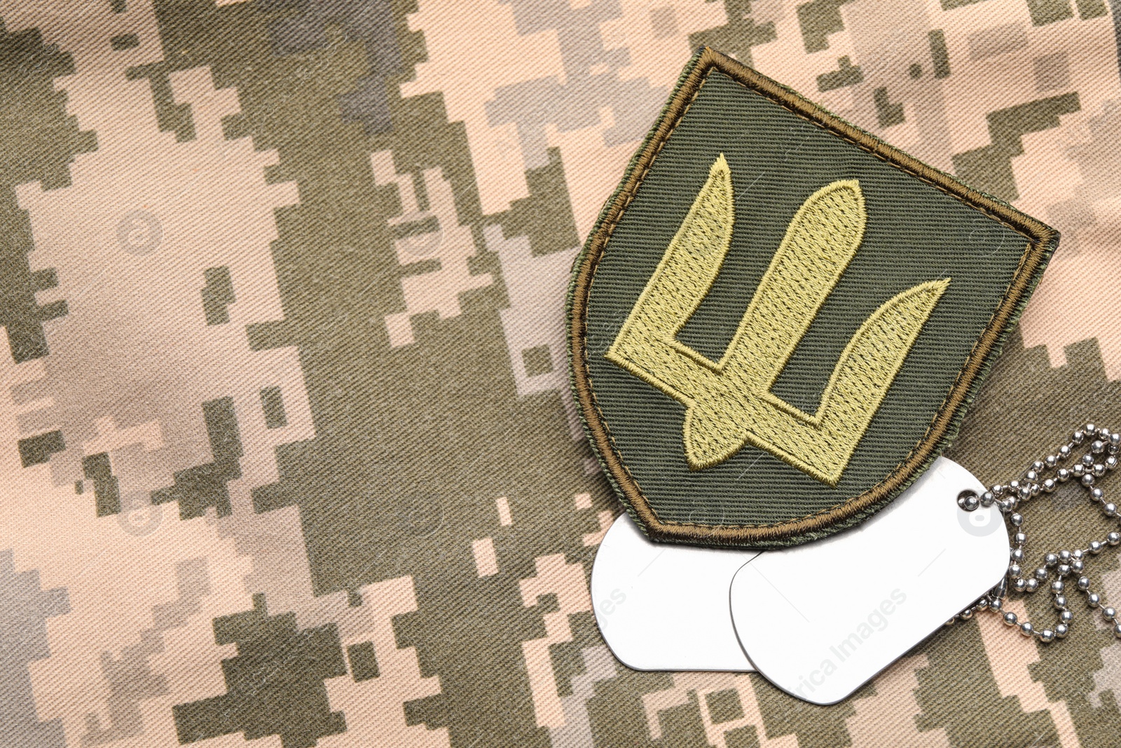 Photo of Military ID tags and patch on pixel Ukrainian camouflage, flat lay. Space for text