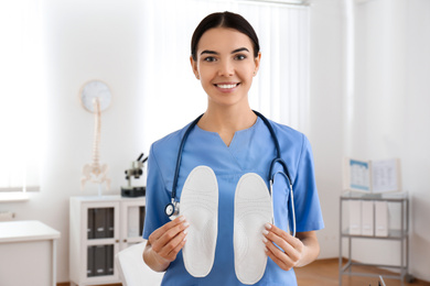 Young female orthopedist showing insoles in clinic