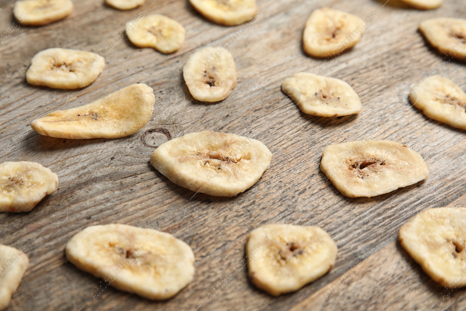 Photo of Composition with banana slices on wooden table. Dried fruit as healthy snack