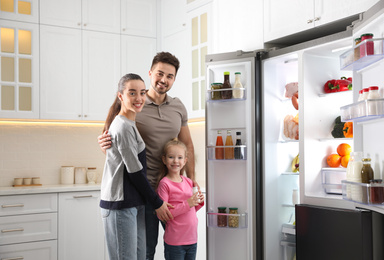 Happy family near open refrigerator in kitchen