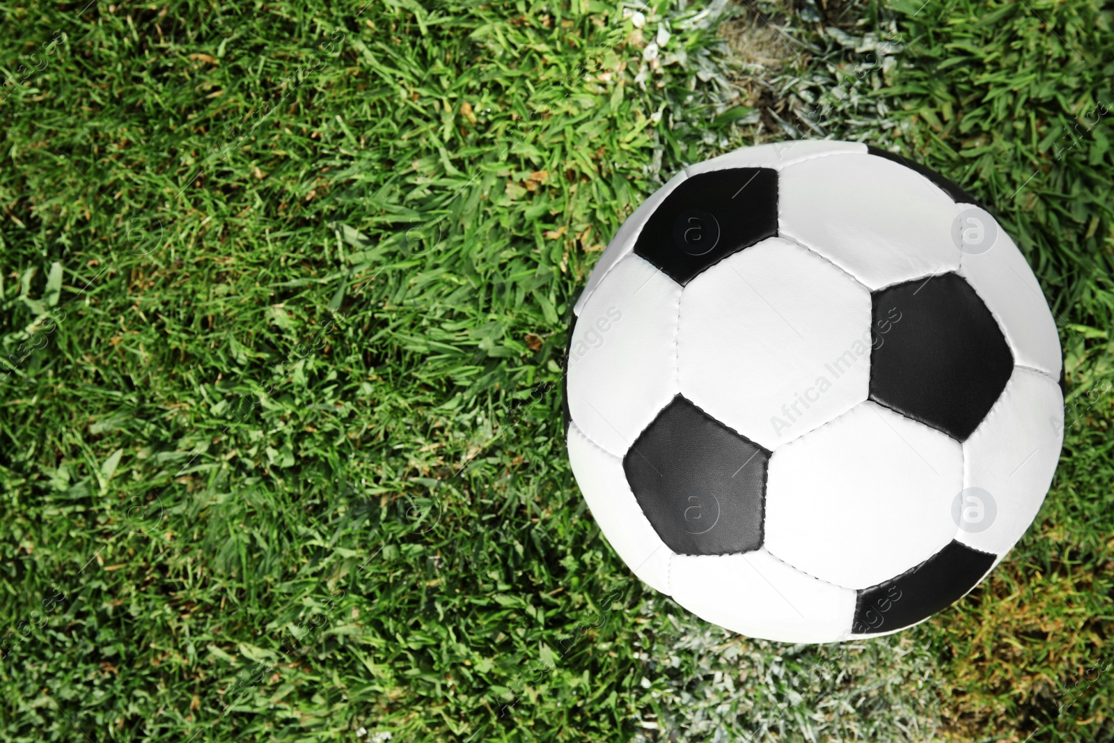 Photo of Soccer ball on fresh green football field grass, top view. Space for text