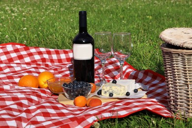 Photo of Picnic blanket with delicious food and wine outdoors on summer day