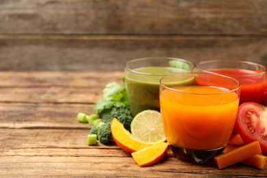 Photo of Delicious vegetable juices and fresh ingredients on wooden table. Space for text