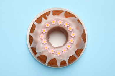 Photo of Delicious Easter cake decorated with sprinkles on light blue background, top view