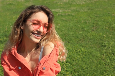 Photo of Portrait of happy woman with heart shaped glasses on green lawn