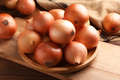 Many ripe onions on wooden table, closeup