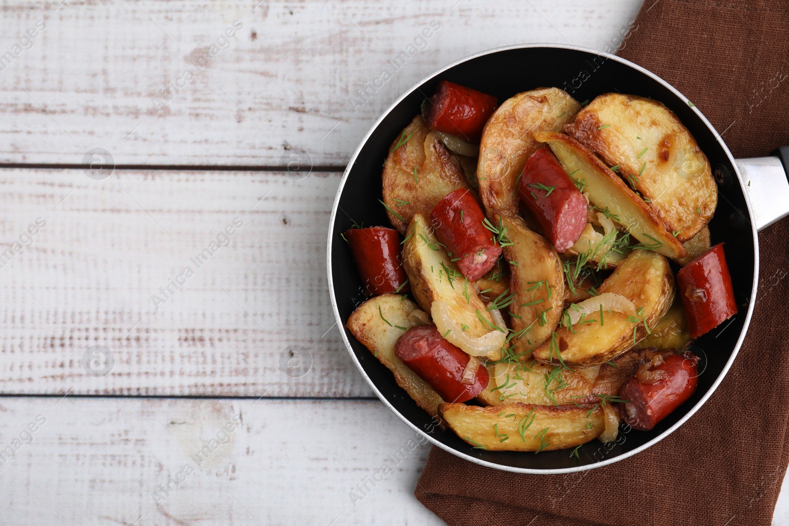 Photo of Fried potatoes with thin dry smoked sausages on white wooden table, top view. Space for text