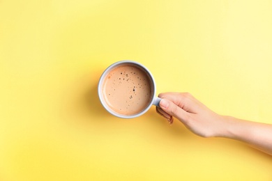 Photo of Young woman with cup of delicious hot coffee on color background, top view