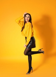 Beautiful young woman posing on yellow background. Halloween party