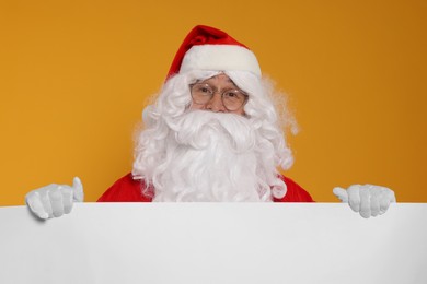 Photo of Santa Claus holding blank poster on orange background