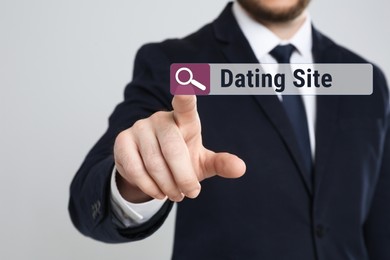 Man pointing at search bar with request Dating Site on light grey background, closeup