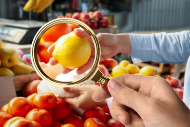 Woman with magnifying glass focusing on lemon, closeup. Food control 