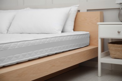 Photo of Wooden bed with soft white mattress and pillows indoors