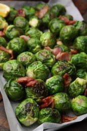 Photo of Delicious roasted Brussels sprouts and bacon in baking dish on table, closeup