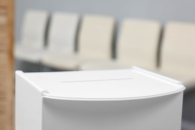 Photo of White ballot box on blurred background, closeup. Space for text