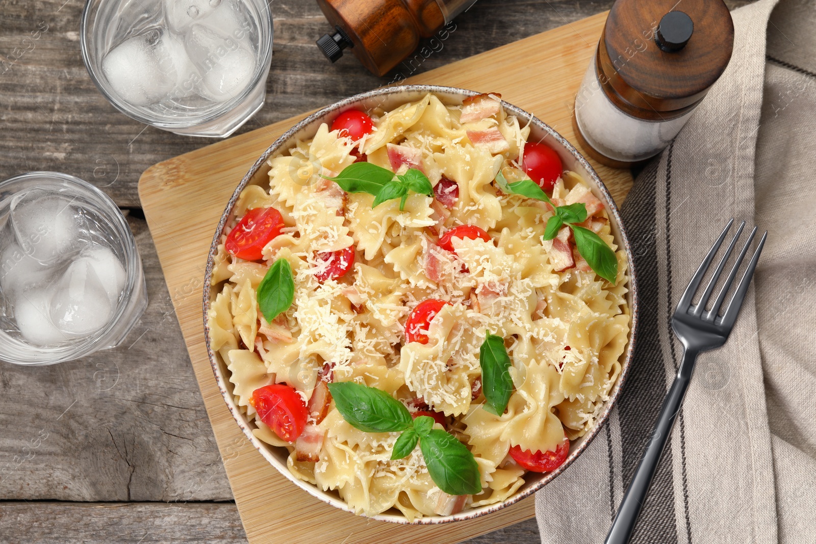Photo of Delicious pasta with tomatoes, basil and parmesan cheese served on wooden table, flat lay