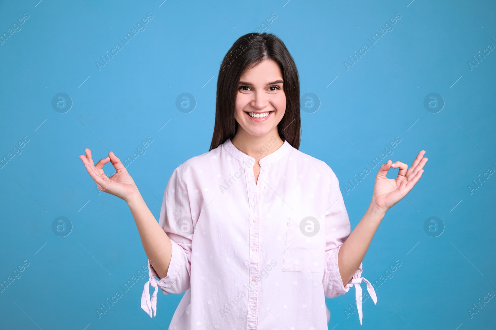 Photo of Young woman meditating on light blue background. Stress relief exercise