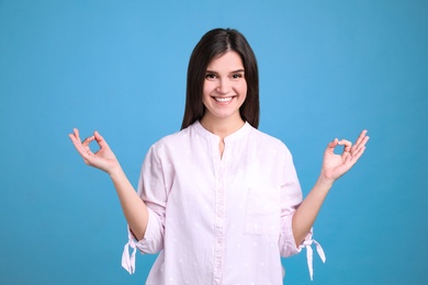 Young woman meditating on light blue background. Stress relief exercise