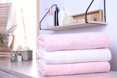 Photo of Stack of fresh towels on table in bathroom. Space for text