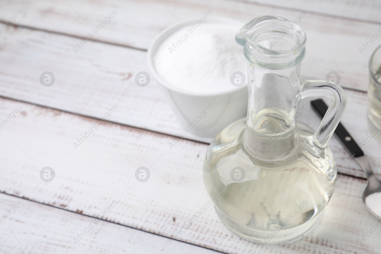 Photo of Vinegar and baking soda on white wooden table, space for text