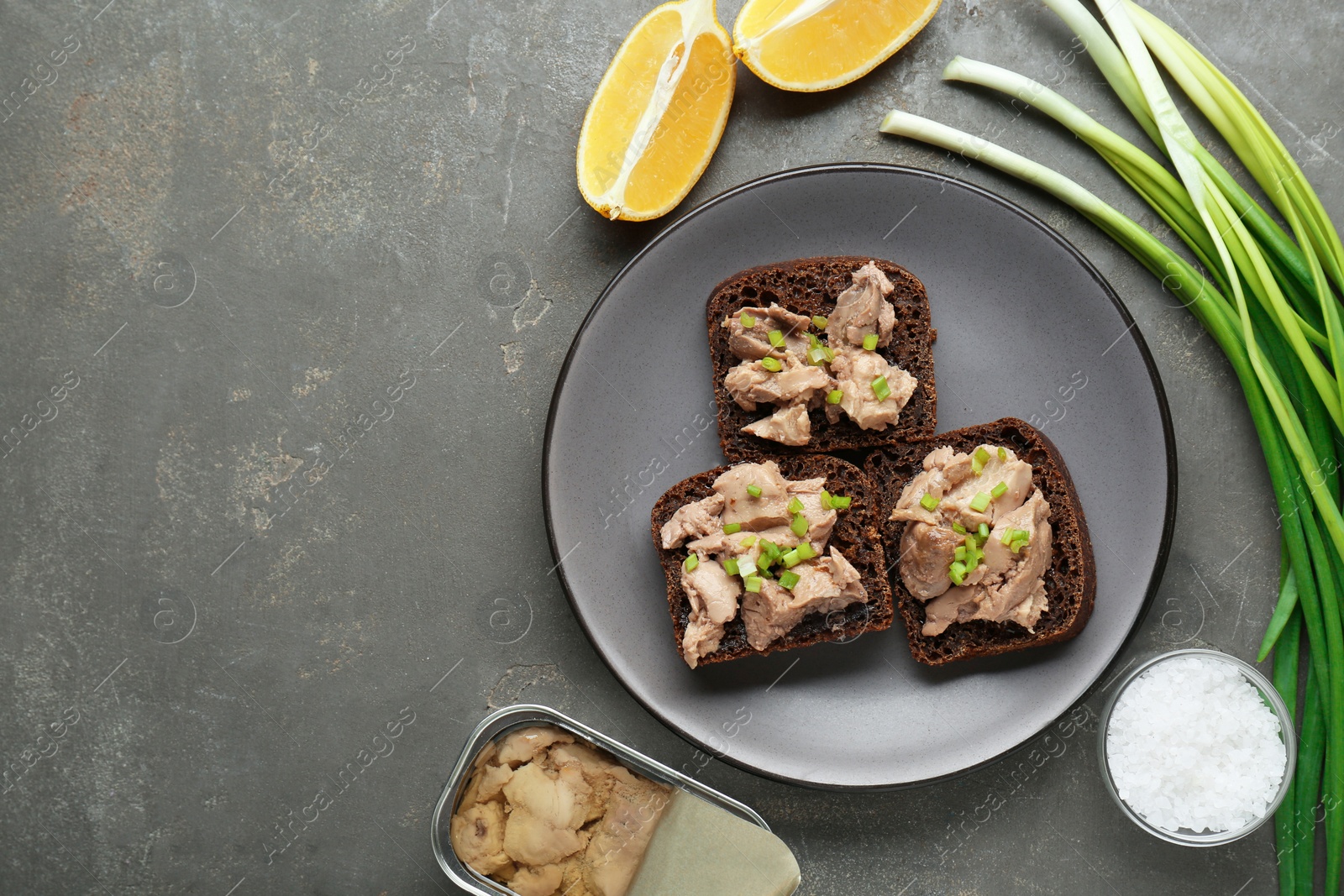 Photo of Tasty sandwiches with cod liver and different products on light grey table, flat lay. Space for text