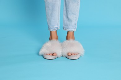 Photo of Woman in fluffy slippers on light blue background, closeup