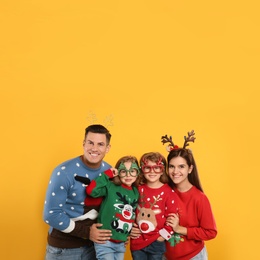 Photo of Family in Christmas sweaters and festive accessories on yellow background