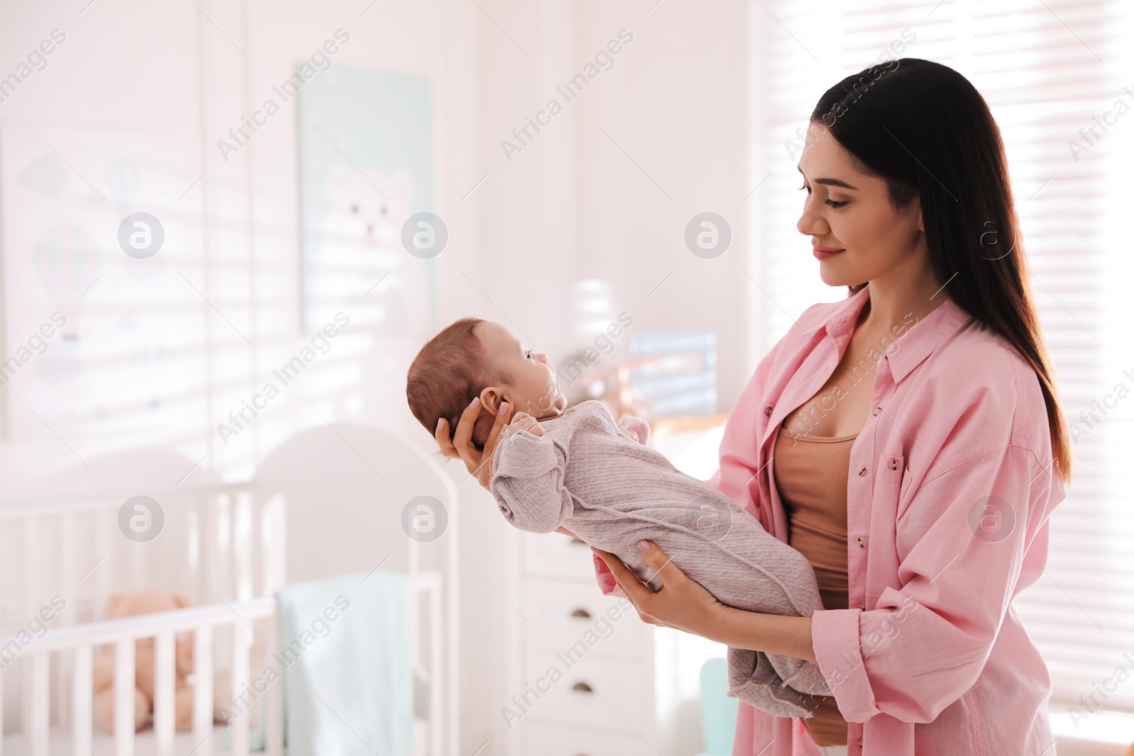 Photo of Young woman with her cute baby at home, space for text