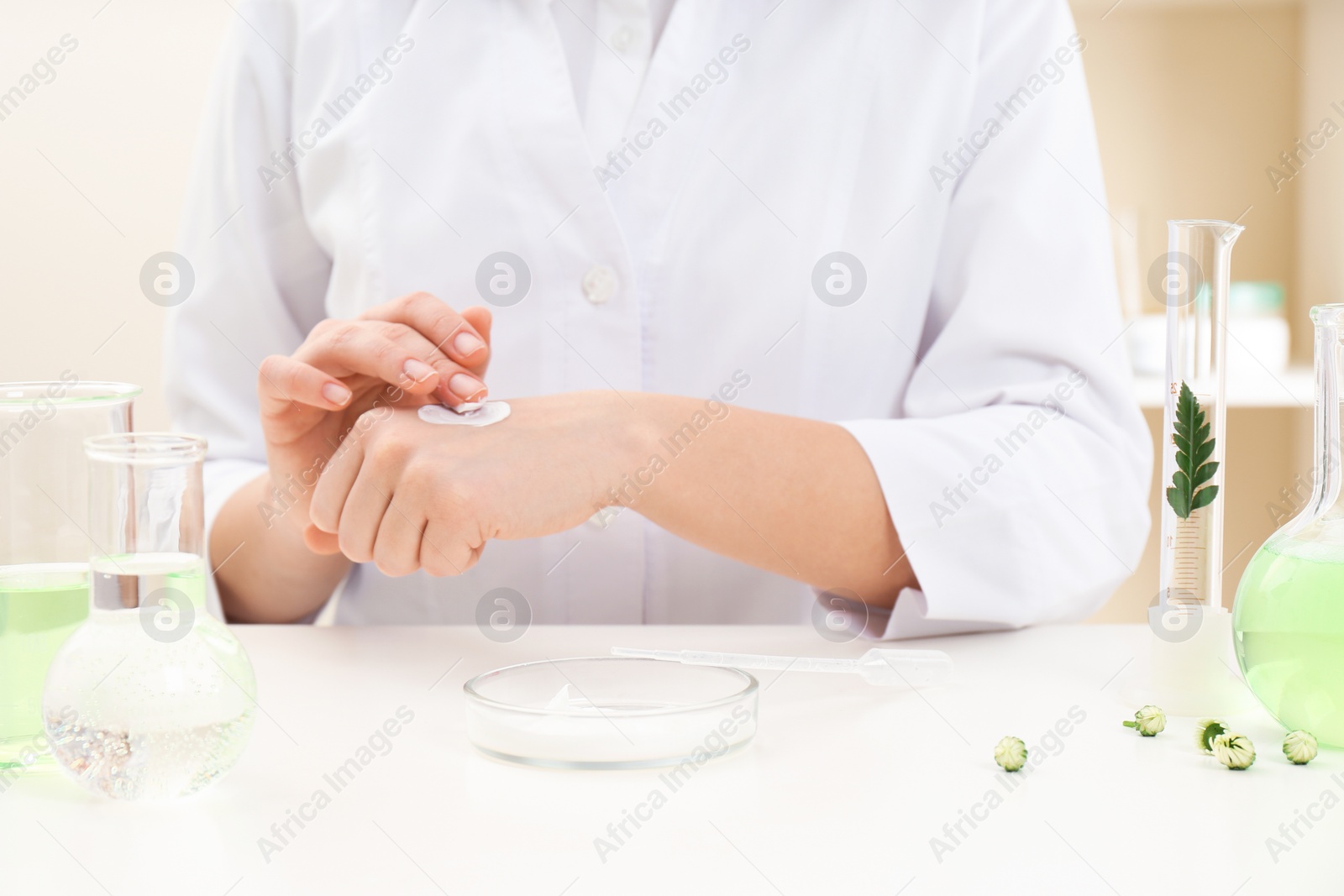 Photo of Female dermatologist testing skin care product at table, closeup