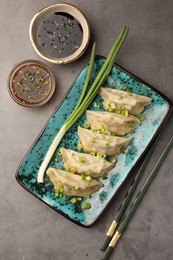Delicious gyoza (asian dumplings) served on gray table, flat lay.