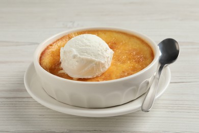 Photo of Delicious creme brulee with scoop of ice cream and spoon on white wooden table