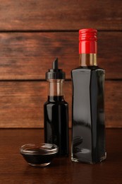 Photo of Bottles and bowl with soy sauce on wooden table