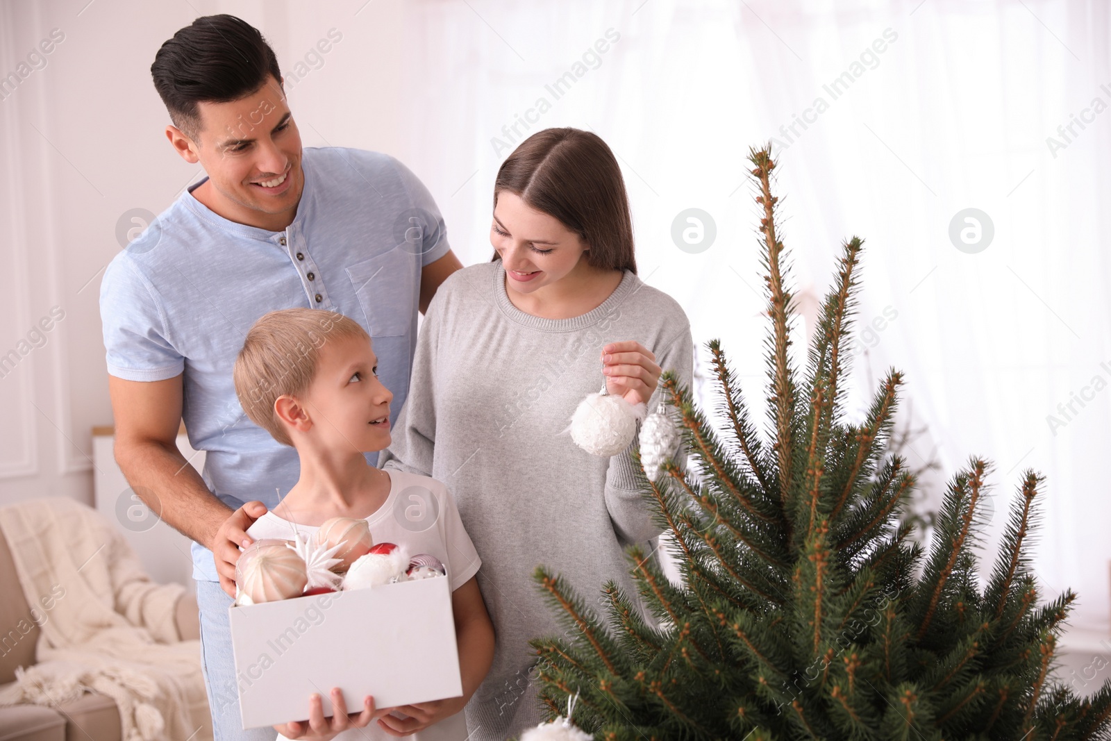 Photo of Happy family with cute child decorating Christmas tree together at home