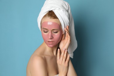Photo of Young woman with pomegranate face mask on light blue background