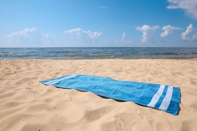 Photo of Blue striped beach towel on sandy seashore