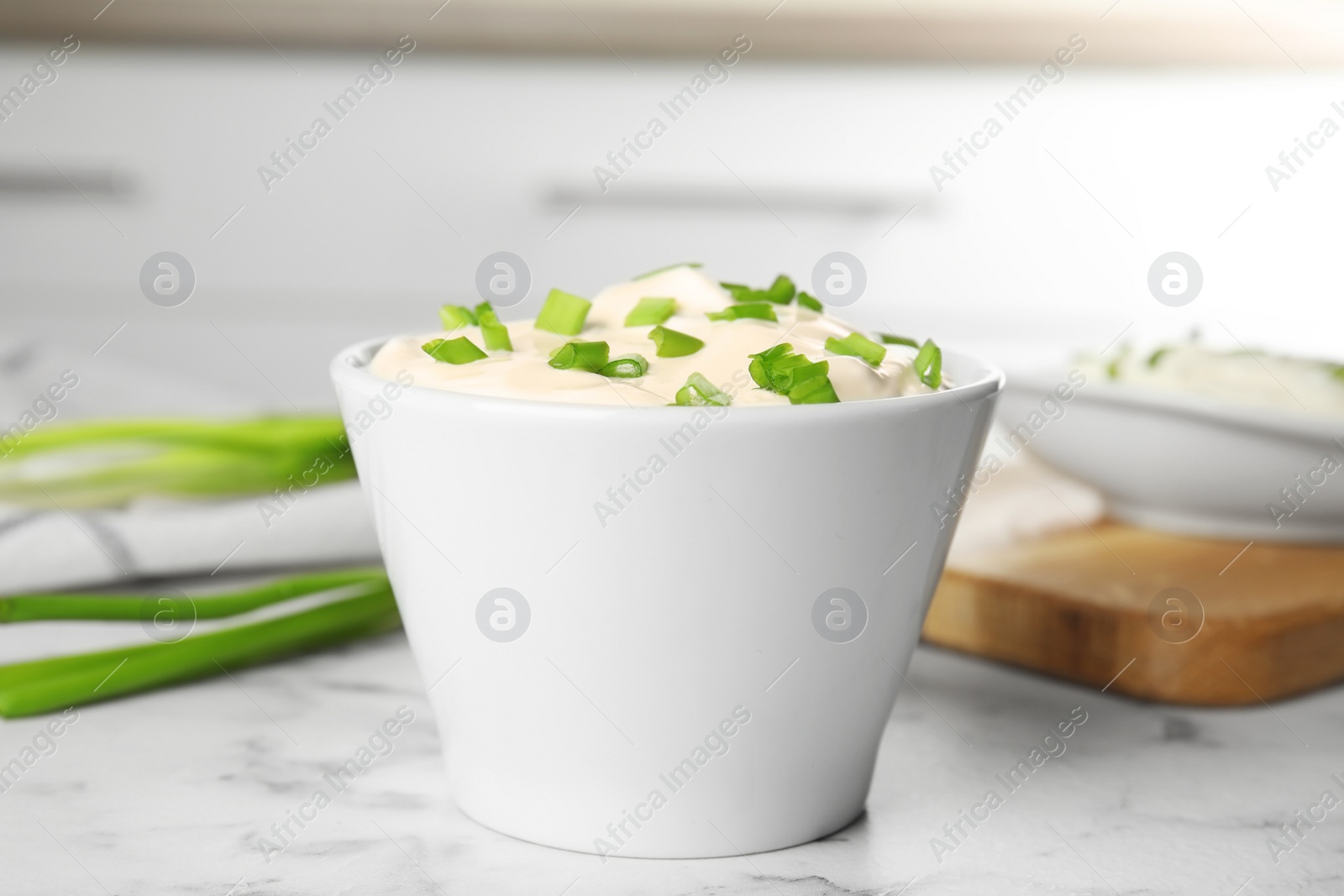 Photo of Fresh sour cream with onion on white marble table