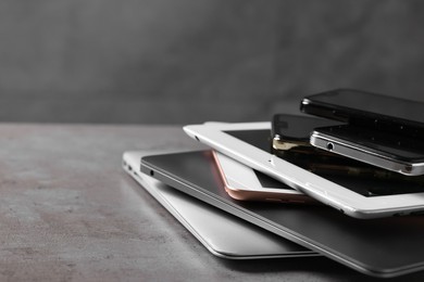 Photo of Many different modern gadgets on grey table, closeup. Space for text