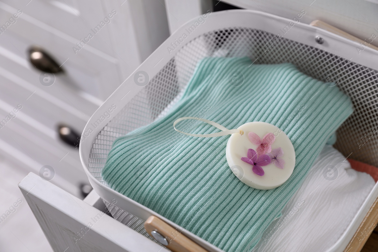 Photo of Basket with scented wax sachet and clothes in dresser drawer indoors, closeup