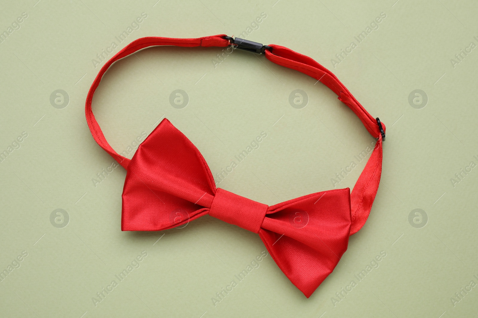 Photo of Stylish red bow tie on pale green background, top view