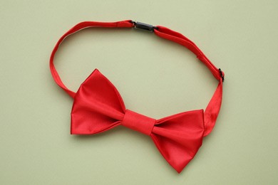 Stylish red bow tie on pale green background, top view