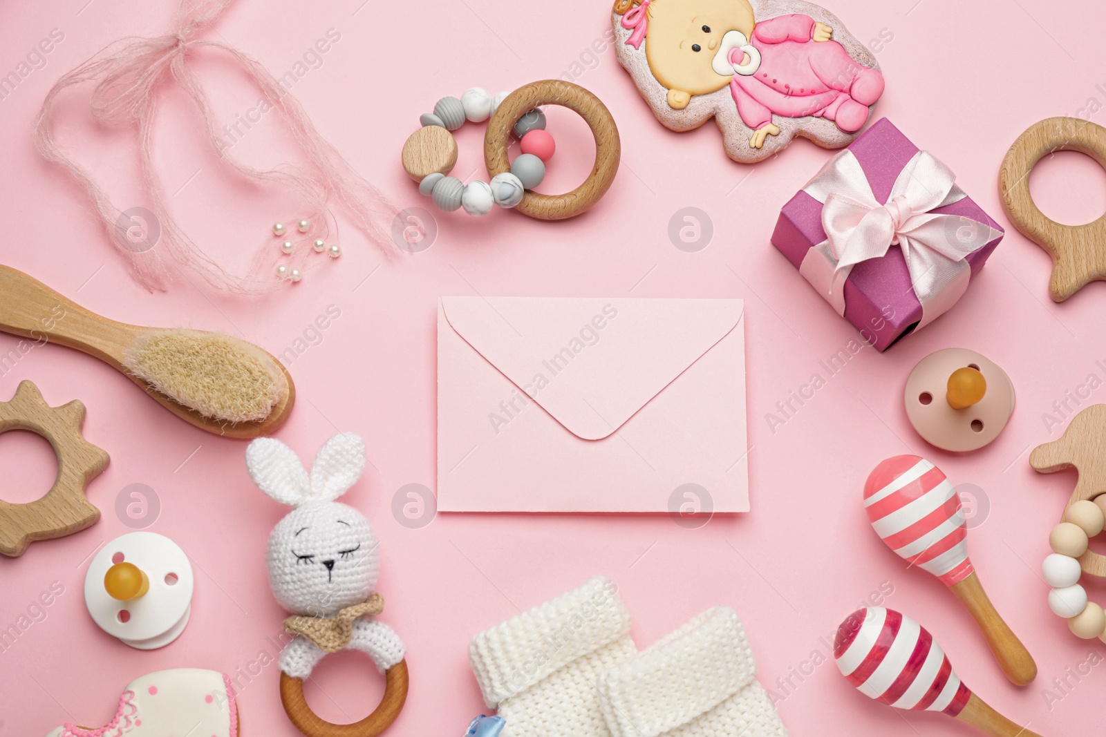 Photo of Envelope for baby shower and accessories on light pink background, flat lay