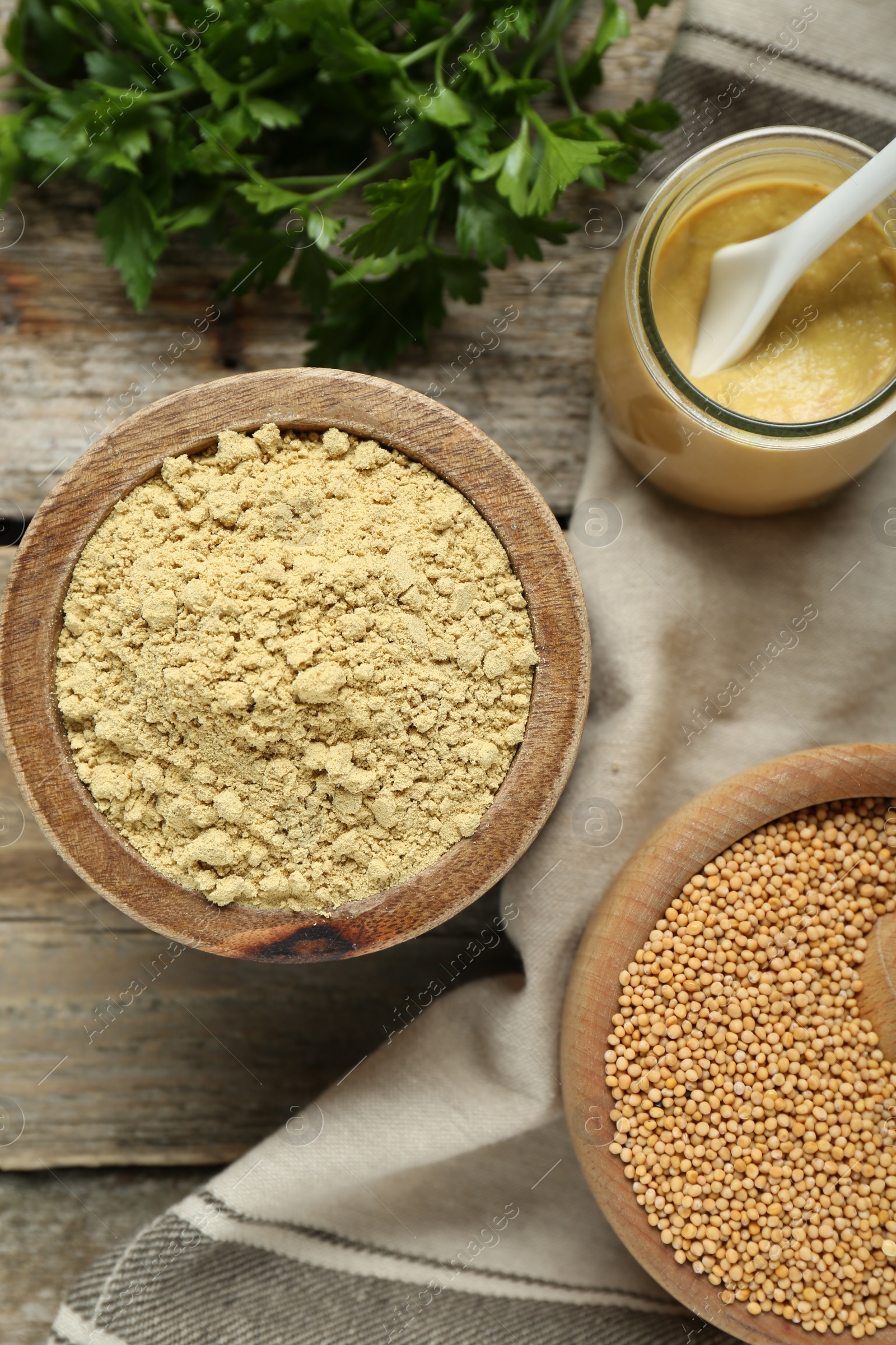 Photo of Flat lay composition with mustard powder, seeds and parsley on wooden table