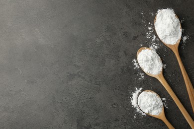 Baking powder in spoons on grey textured table, flat lay. Space for text