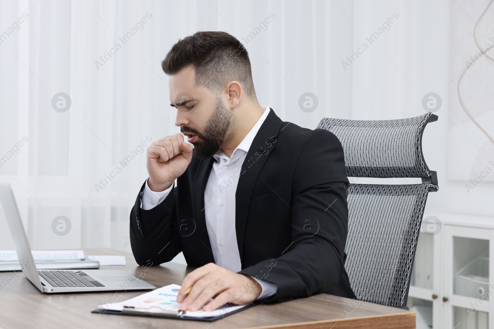 Photo of Sick man coughing at workplace in office