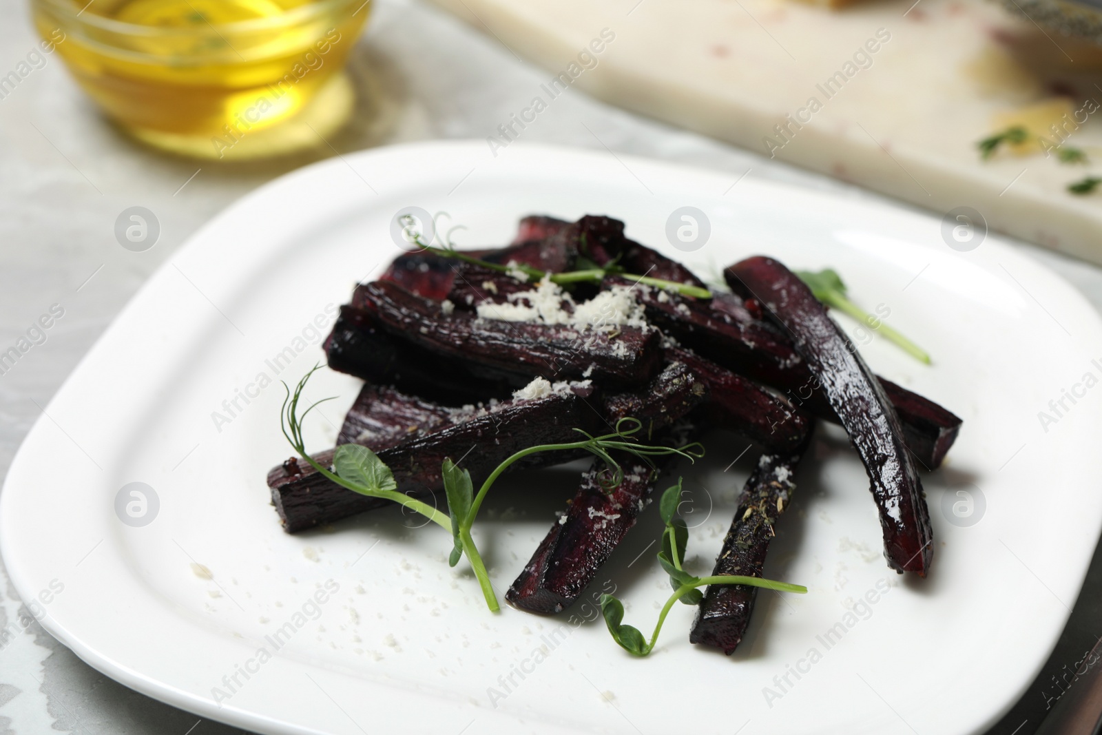 Photo of Tasty baked black carrot with pea sprouts and grated cheese on table, closeup